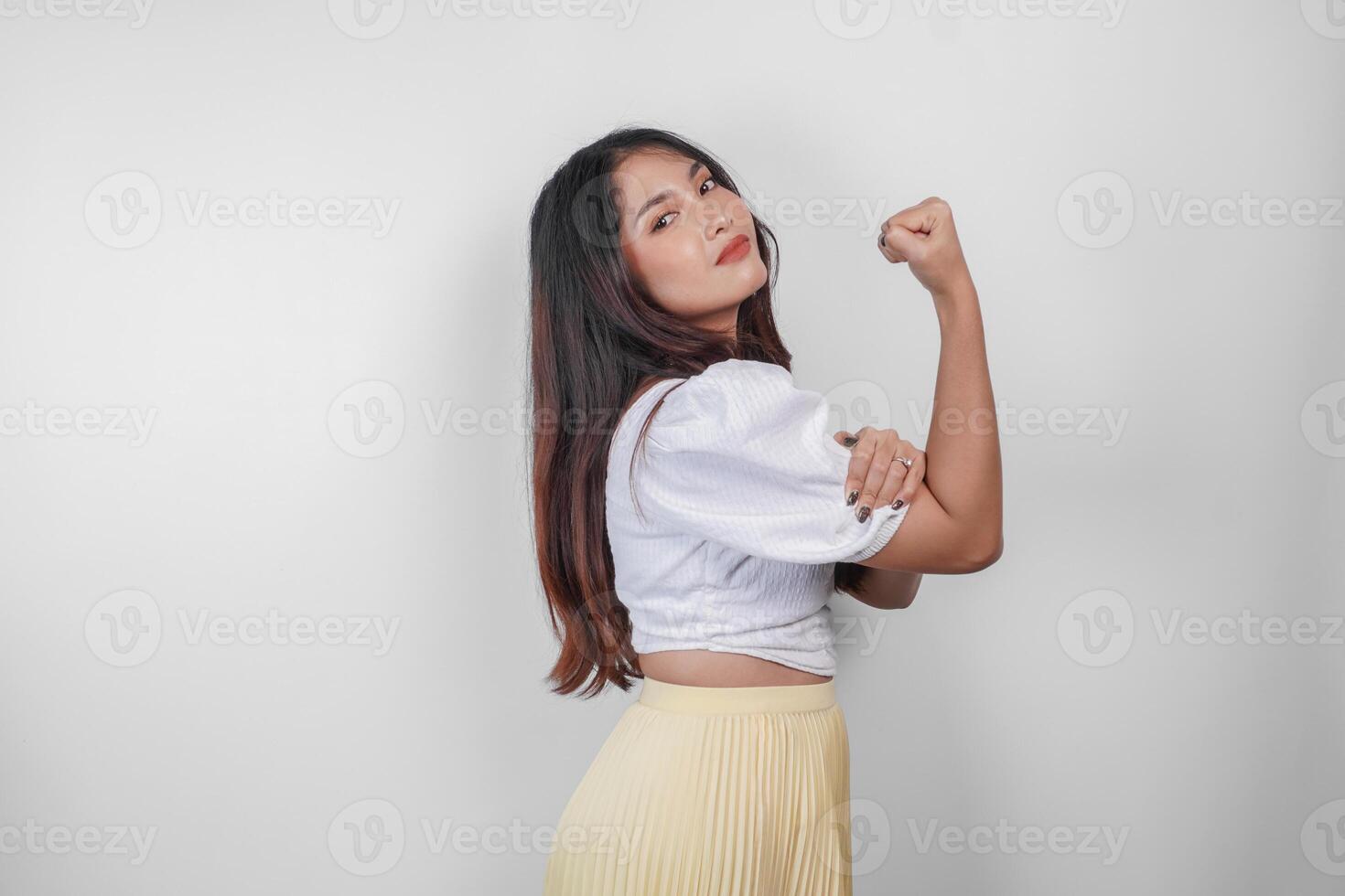 A portrait of Asian woman showing strong gesture by lifting her arms and muscles smiling proudly. photo