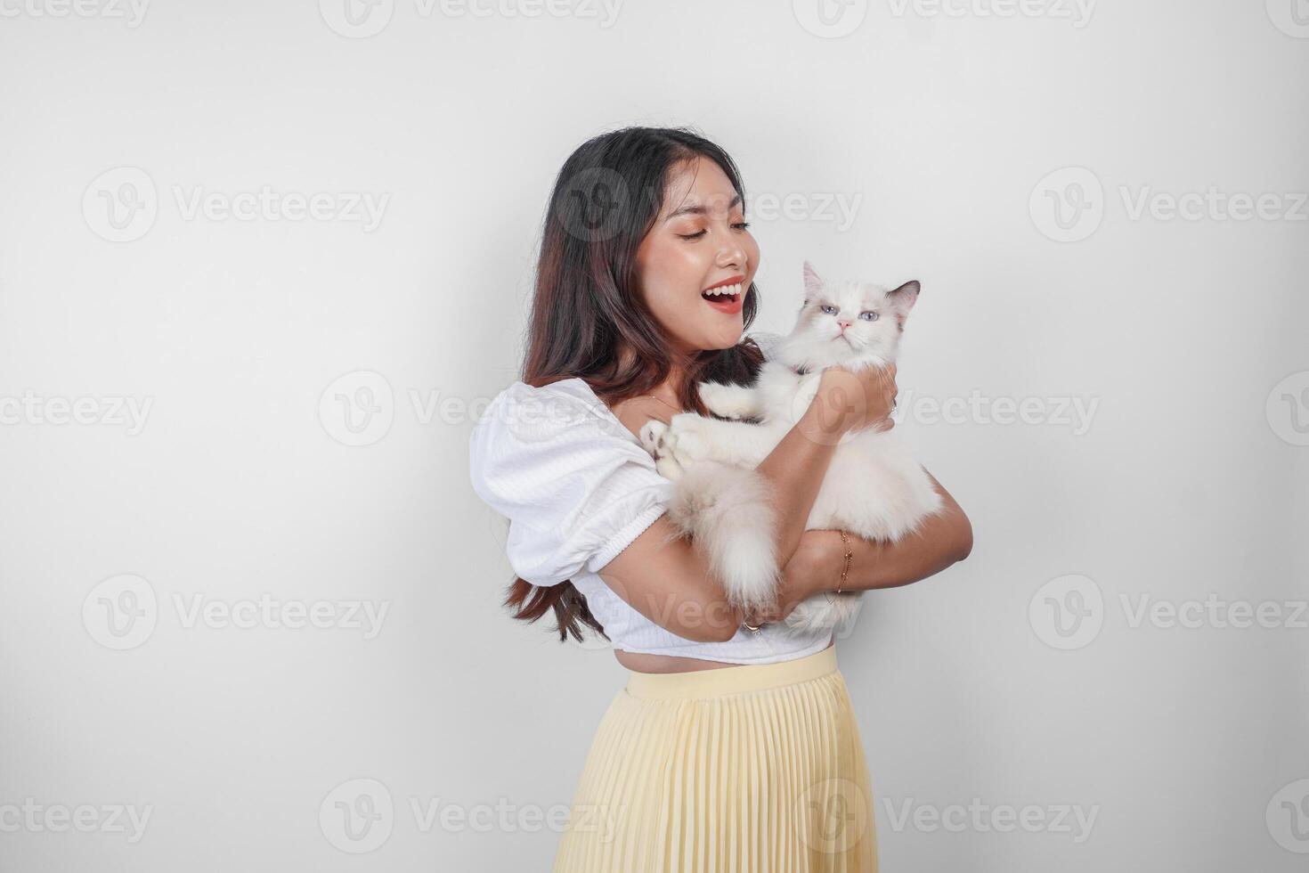 retrato de joven asiático mujer participación linda muñeca de trapo gato con azul ojos. hembra abrazando su linda largo pelo gatito aislado por blanco antecedentes. adorable Doméstico mascota concepto. foto