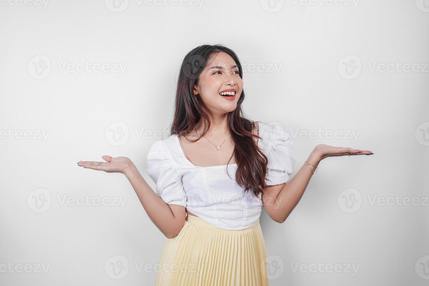 A cheerful Asian woman is pointing copy space beside her, isolated by white background. photo