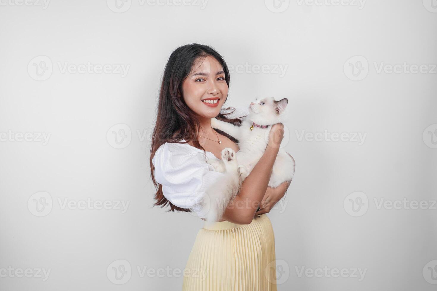 Portrait of young Asian woman holding cute ragdoll cat with blue eyes. Female hugging her cute long hair kitty isolated by white background. Adorable domestic pet concept. photo