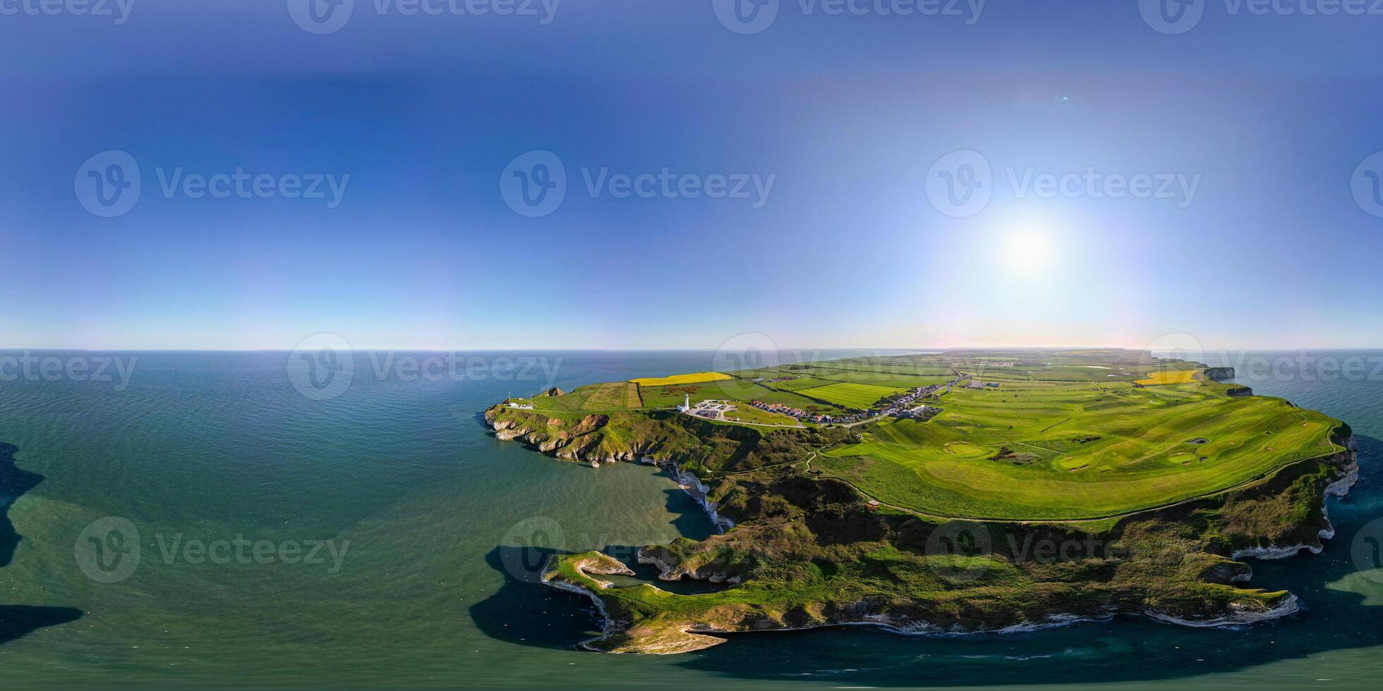 Panoramic aerial view of a lush green island surrounded by blue ocean under a clear sky in Flamborough, England photo