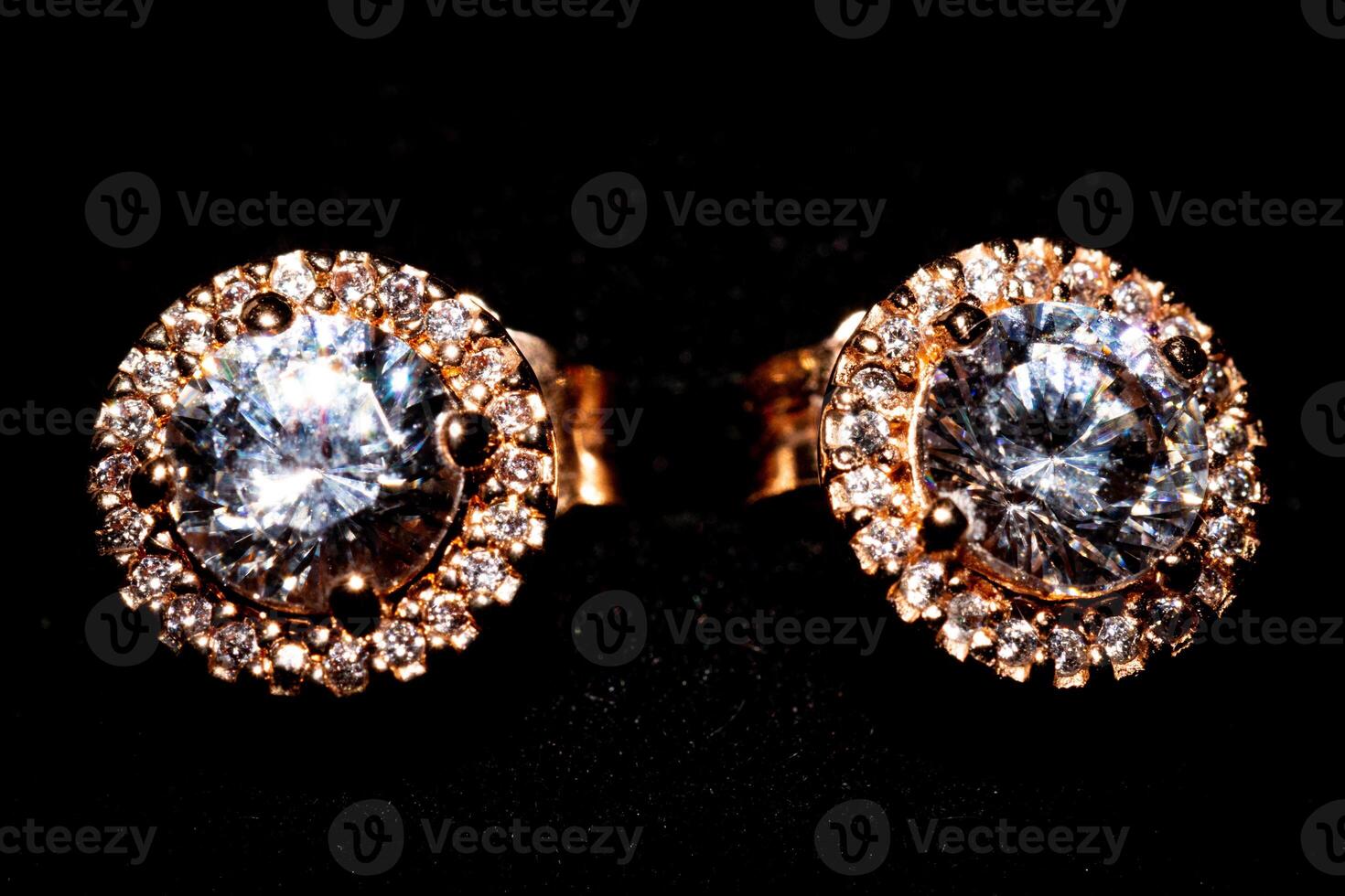 Elegant diamond earrings with gold setting on a black background. photo