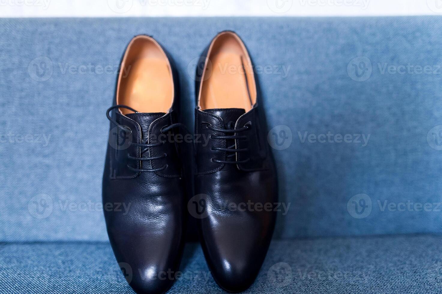 The pair of black leather shoes on a blue background. Closeup. Groom's morning. photo