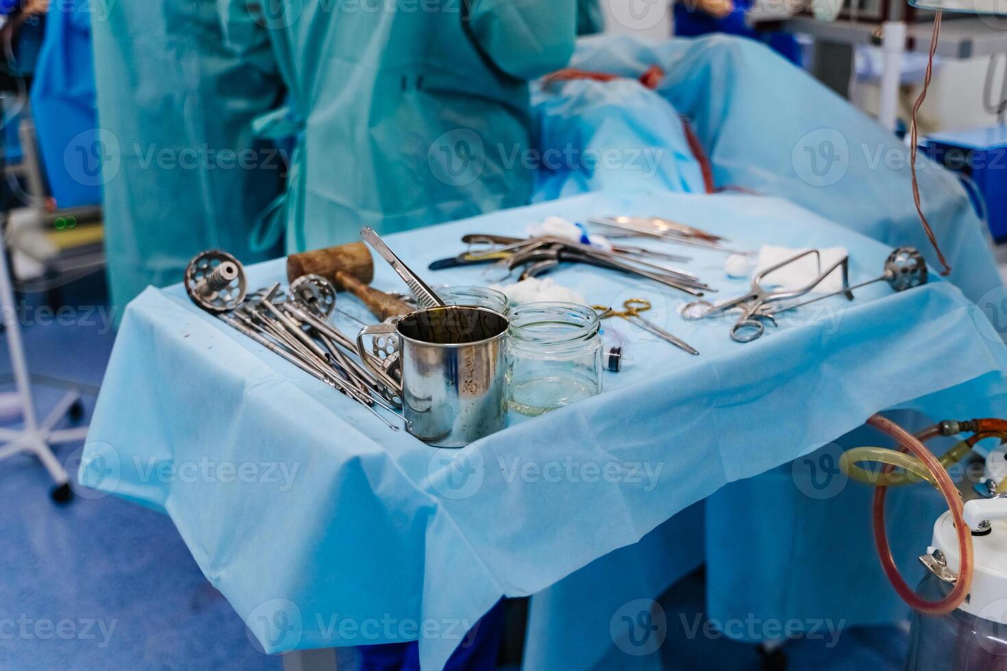 Surgery instruments on table covered by sterile field in surgery operation room with team surgeons in surgery center for interventions with instruments for microsurgery photo