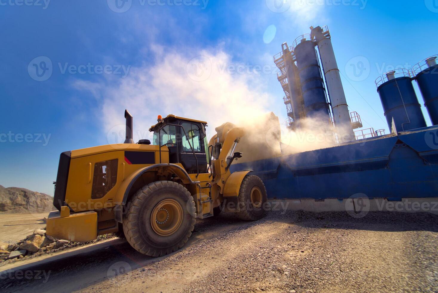 Orange wheel loader excavator in the background of a gravel storage in the open air. Quarry and mining equipment. photo