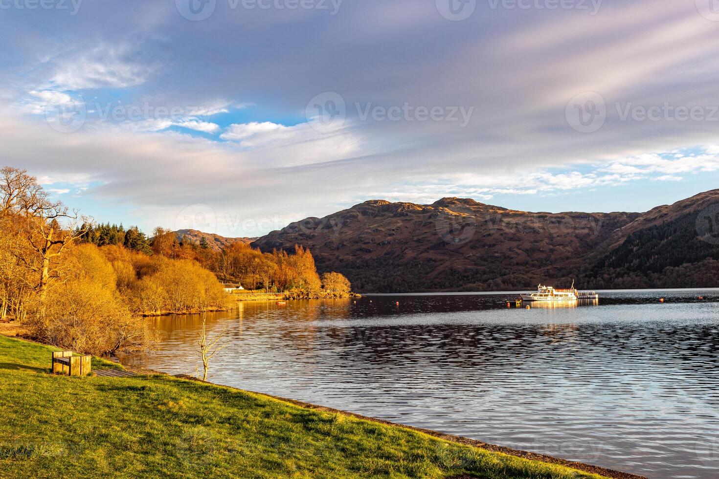 Serene lake with a boat and mountains during sunset, showcasing beautiful natural scenery and tranquil waters. photo