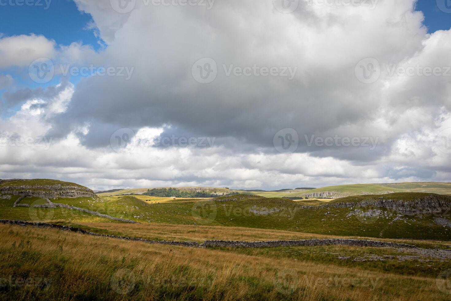 Rolling hills under a dramatic cloudy sky, showcasing the natural beauty of a serene landscape. photo