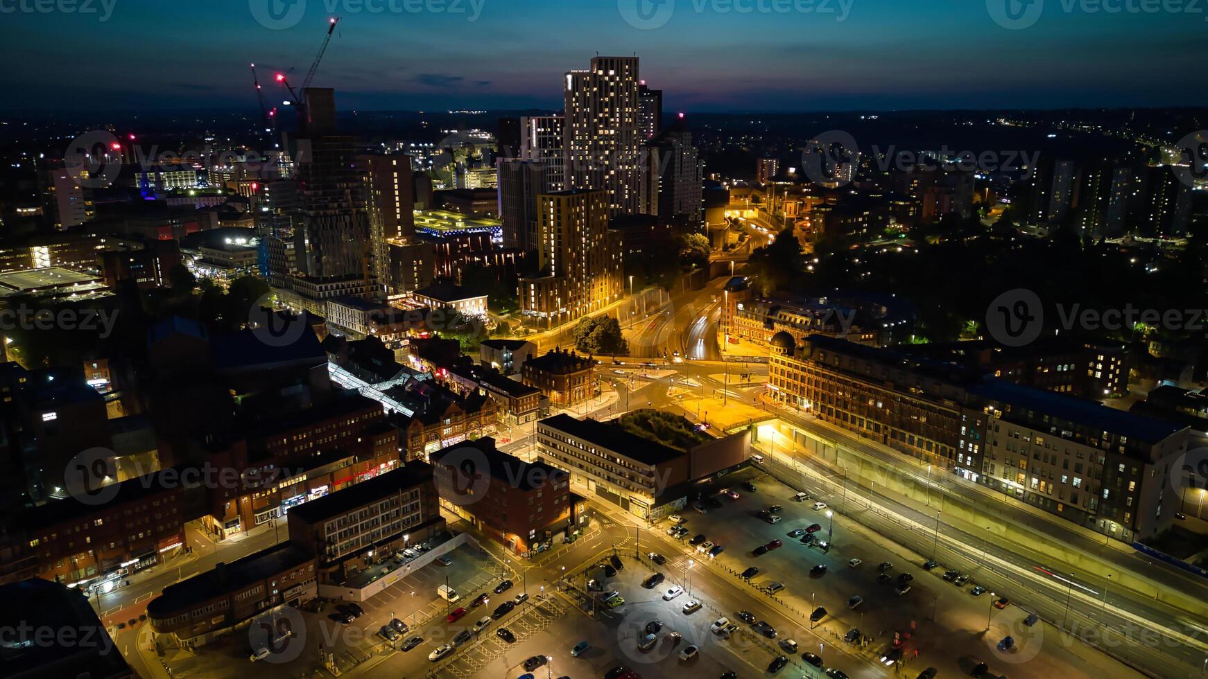 aéreo noche ver de un bullicioso paisaje urbano con iluminado calles y Alto edificios en leeds. foto