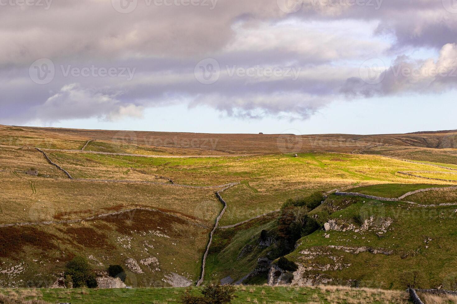 Rolling hills with lush greenery under a dramatic cloudy sky in Yorkshire Dales. photo