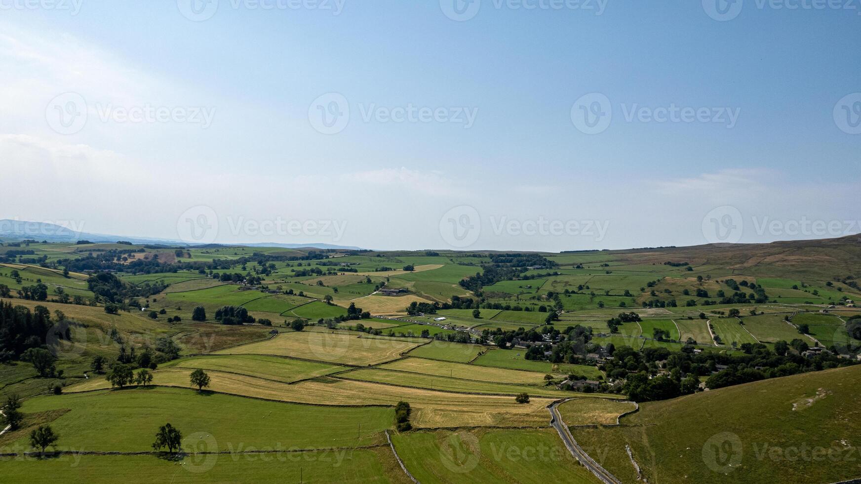 Scenic view of a lush green valley with patchwork fields and a clear sky, ideal for landscape and travel themes. photo