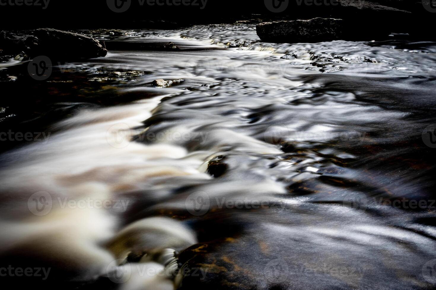 largo exposición de un sereno corriente con suave agua fluido terminado rocas, creando un sedoso efecto. foto