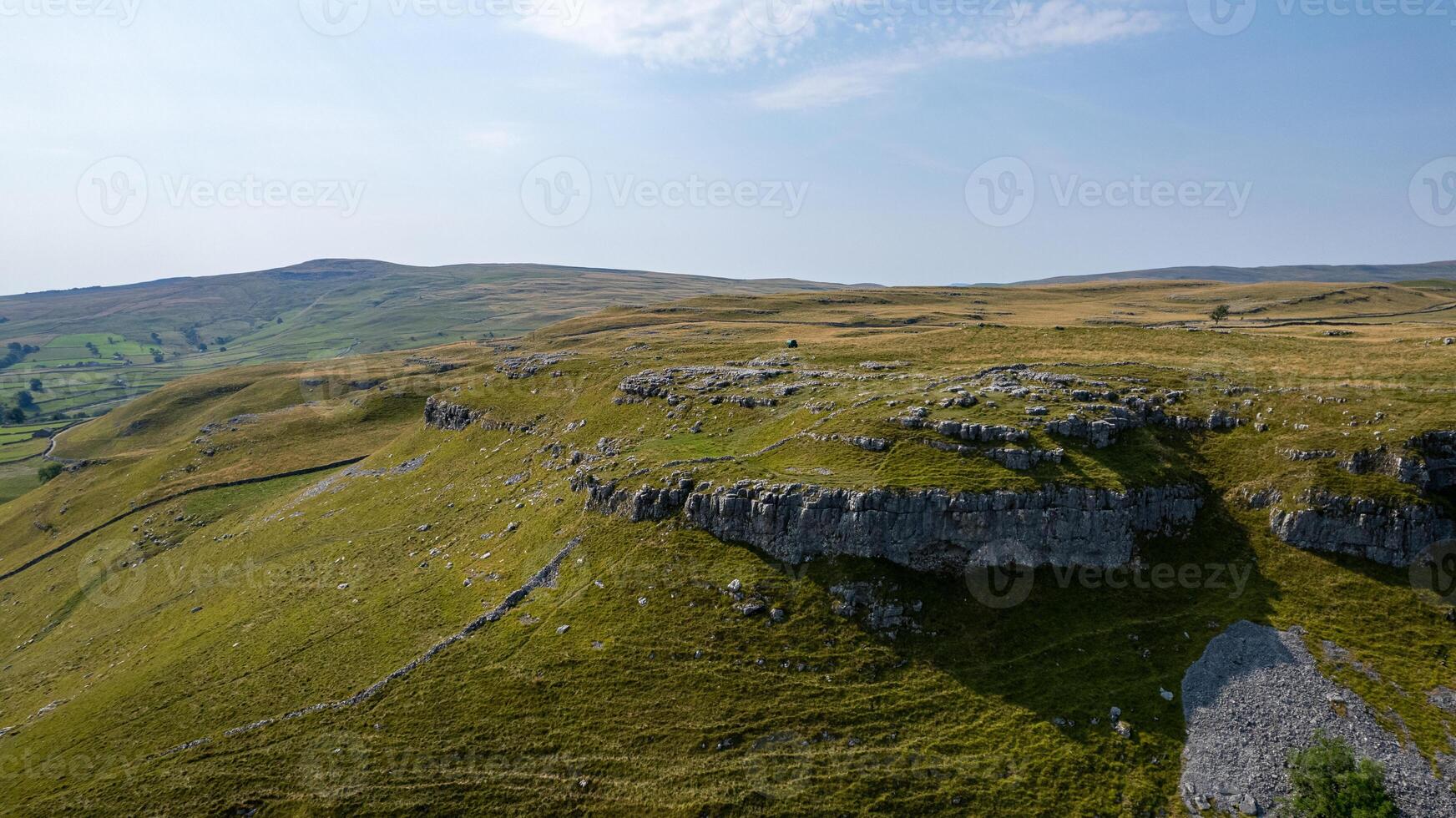 Scenic view of a vast grassy landscape with rocky outcrops under a clear blue sky. photo