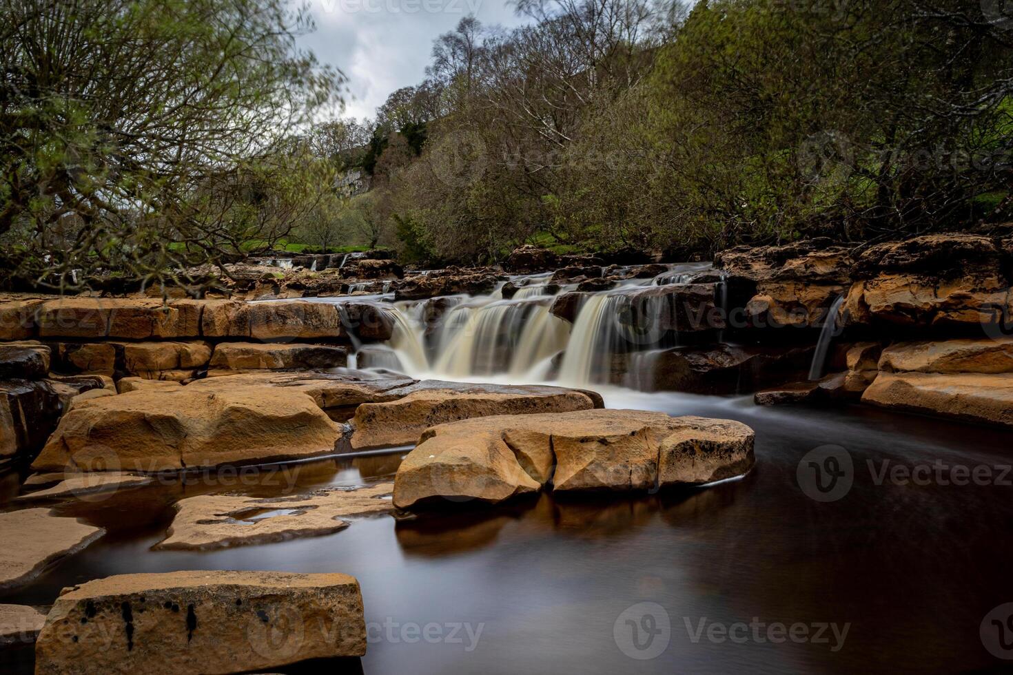 a waterfall is flowing over rocks in a forest photo