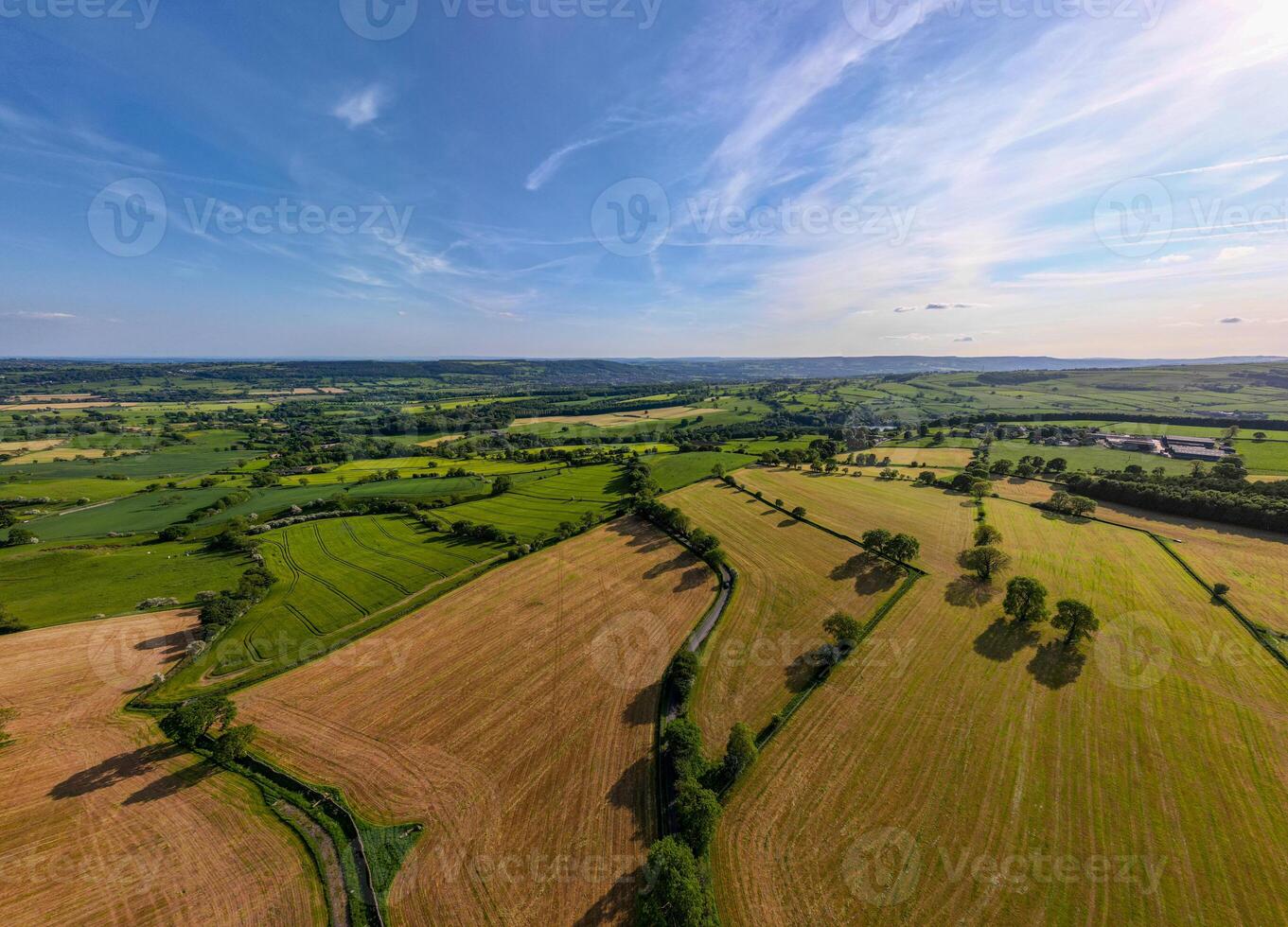 Aerial view of a lush countryside with patchwork fields under a blue sky with wispy clouds. photo