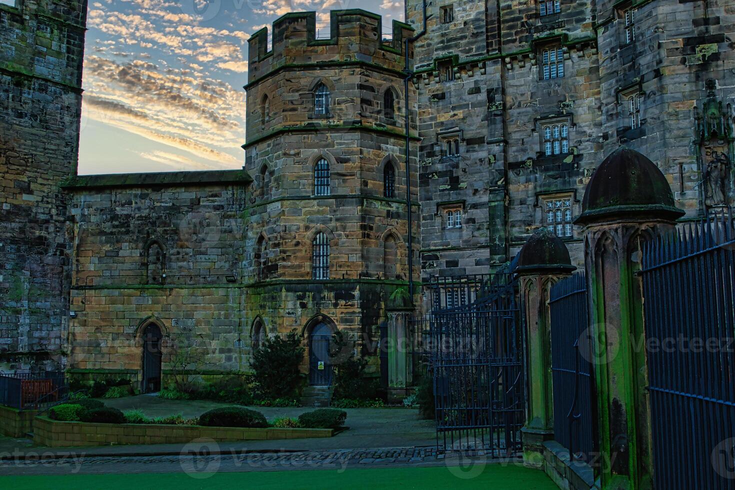 Historic stone castle at dusk with dramatic sky and greenery, suitable for travel and history themes in Lancaster. photo