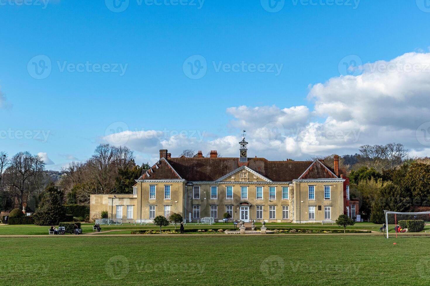 Elegant historical mansion with a lush green lawn under a blue sky with scattered clouds. photo