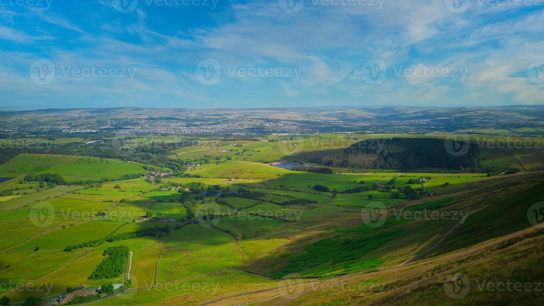 Breathtaking panoramic view of lush green countryside with rolling hills under a clear blue sky in Pendle Hill, England. photo