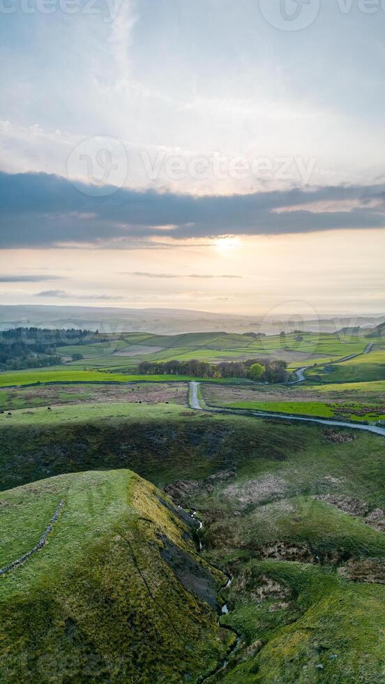 Scenic vertical landscape with rolling hills and a sunset over a tranquil countryside. photo