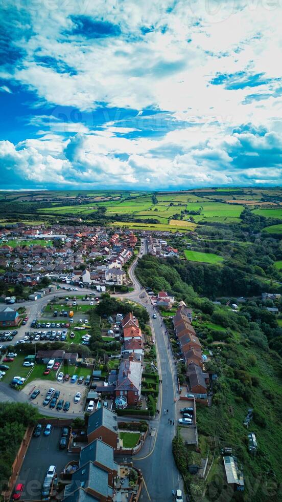 Aerial view of a quaint town with lush greenery under a dynamic sky in Staithes, England. photo