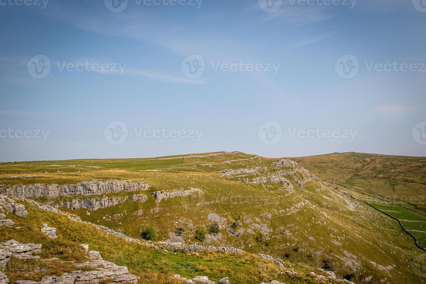 Rolling hills with rocky outcrops under a clear blue sky. photo