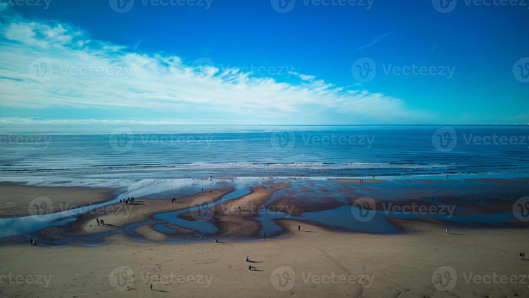 Aerial view of a tranquil beach with patterns in the sand, gentle waves, and a clear blue sky in Backpool, England. photo