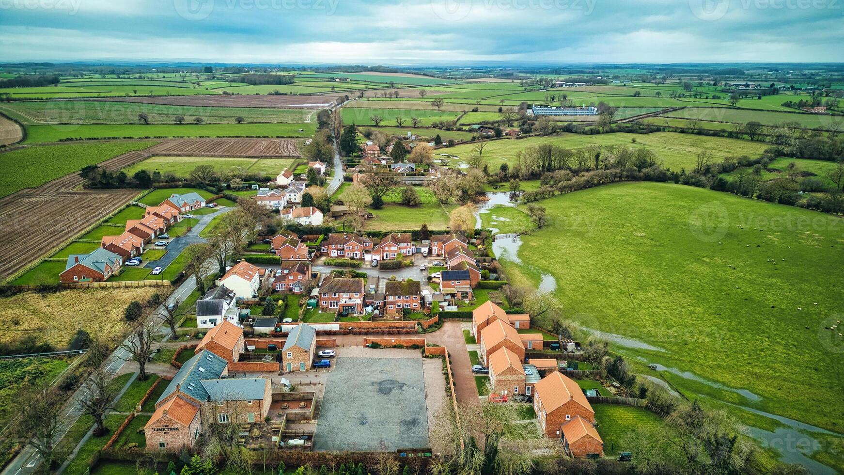 Aerial view of a quaint village surrounded by green fields and farmland, showcasing rural life and landscape. photo