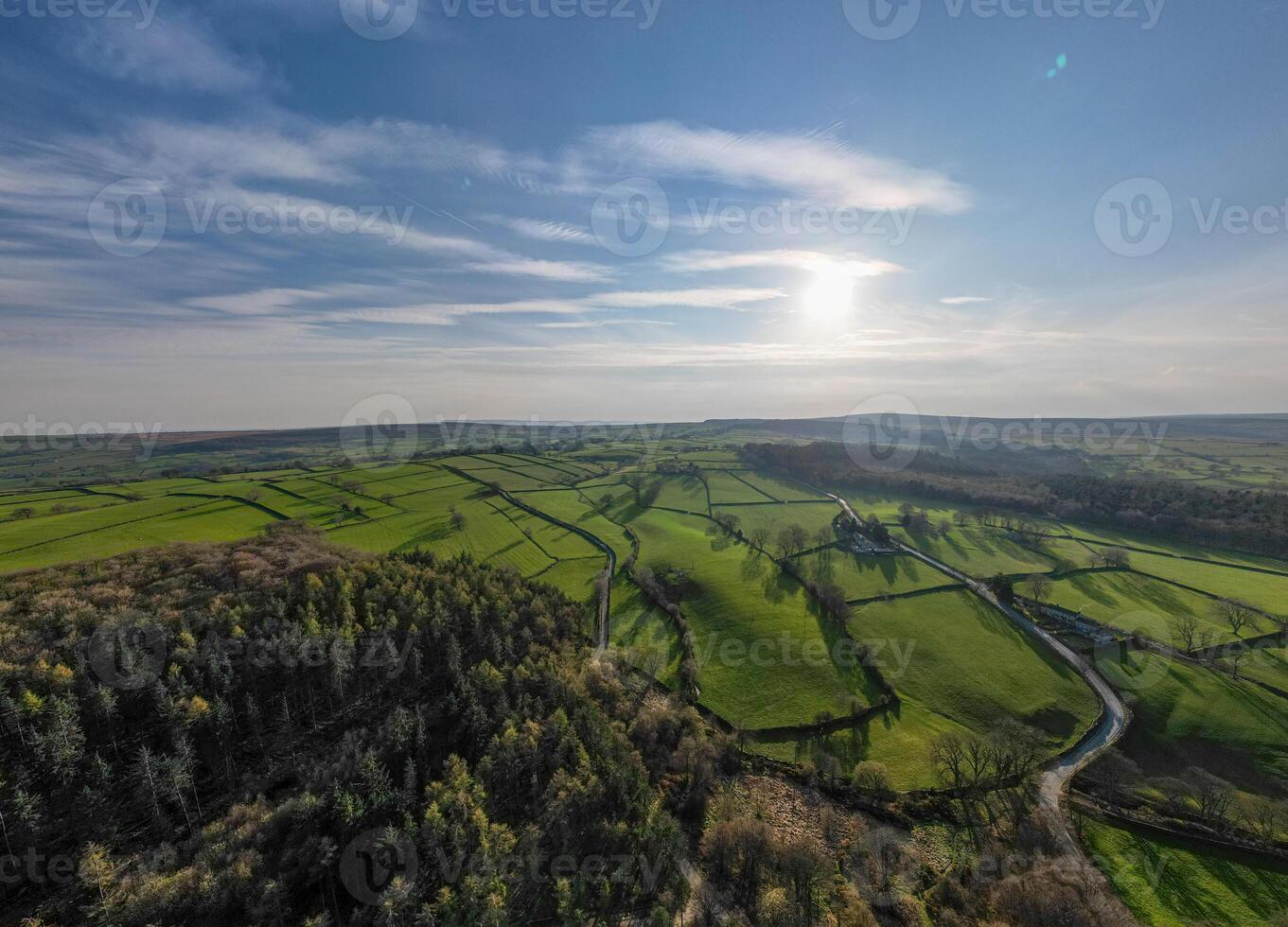 an aerial view of a green countryside and a road photo