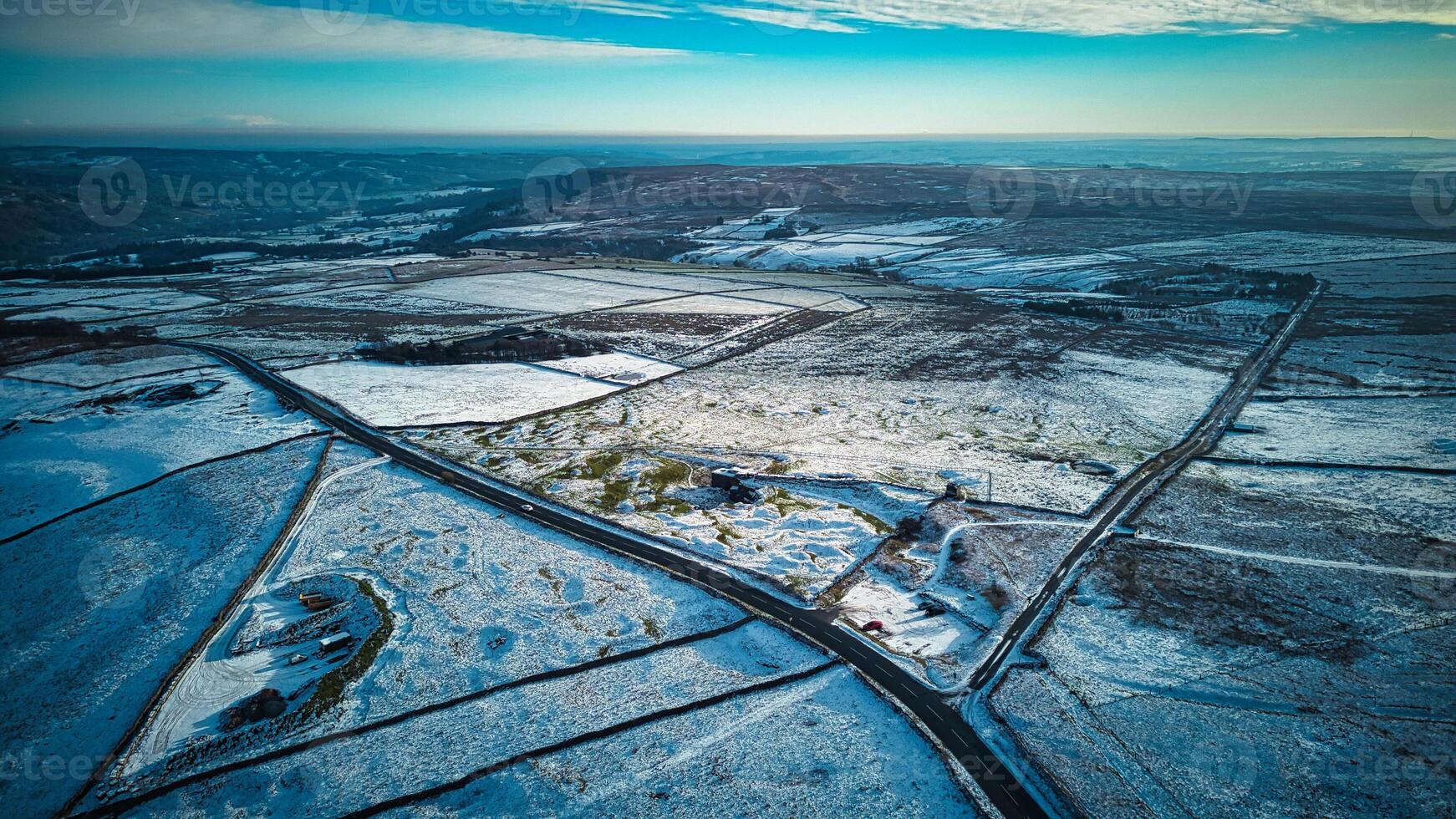 Aerial view of a snowy landscape with roads intersecting under a blue sky at dusk. photo