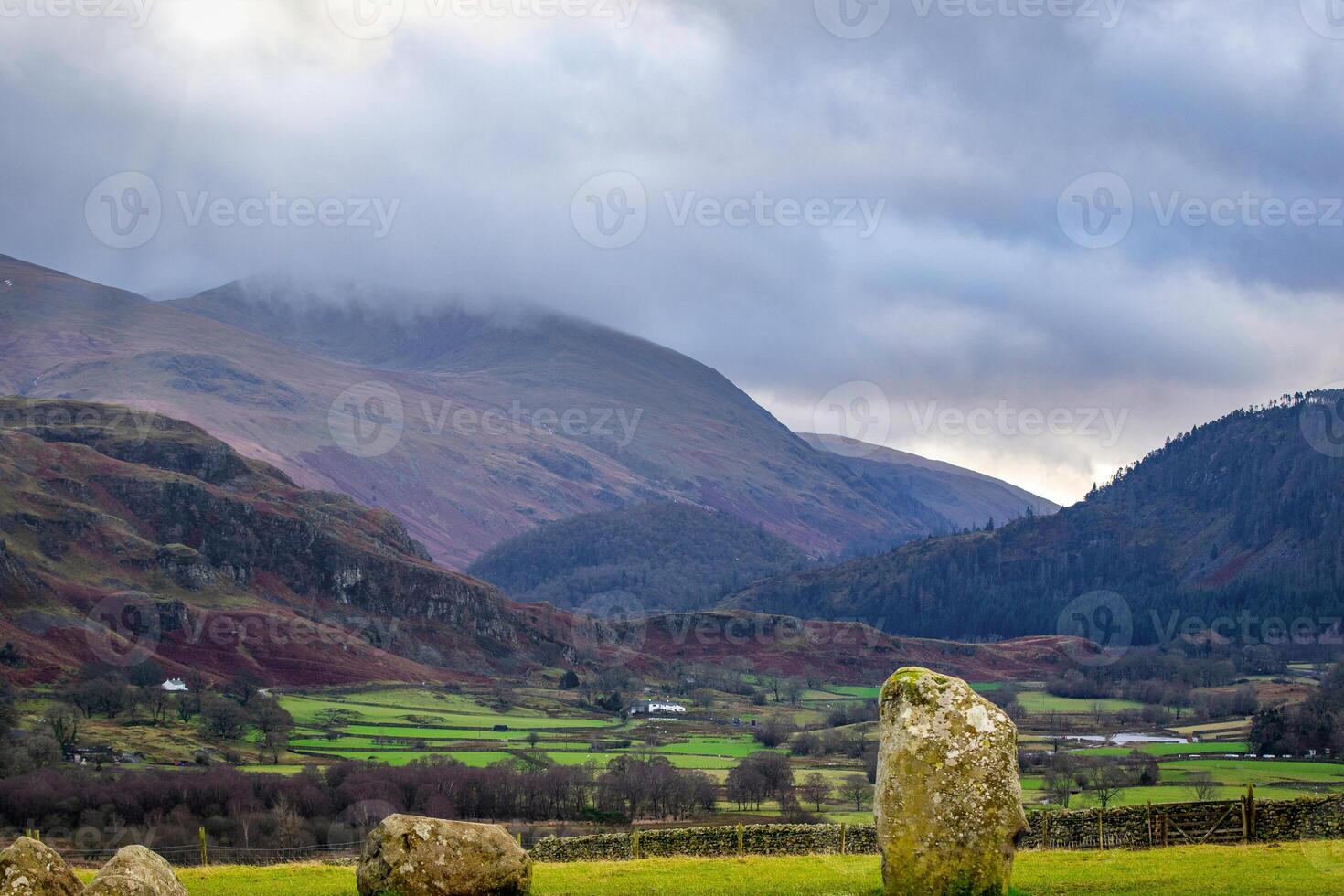 Majestic landscape with sun rays piercing through clouds over green valley and mountains. photo