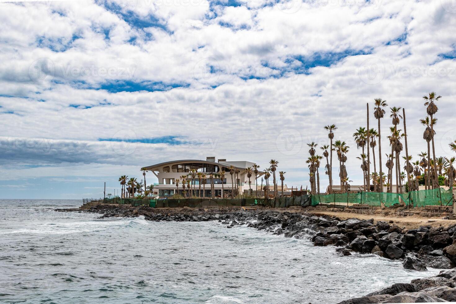 Coastal landscape with palm trees and a pavilion under a cloudy sky in Los Cristianos, Tenerife. photo