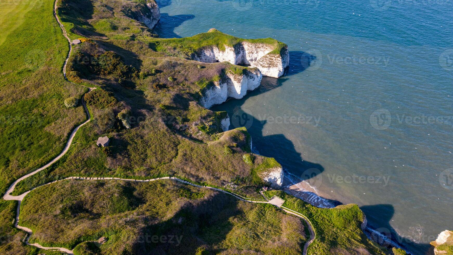 Aerial view of a scenic coastal cliff with greenery and winding paths leading to the beach in Flamborough, England photo