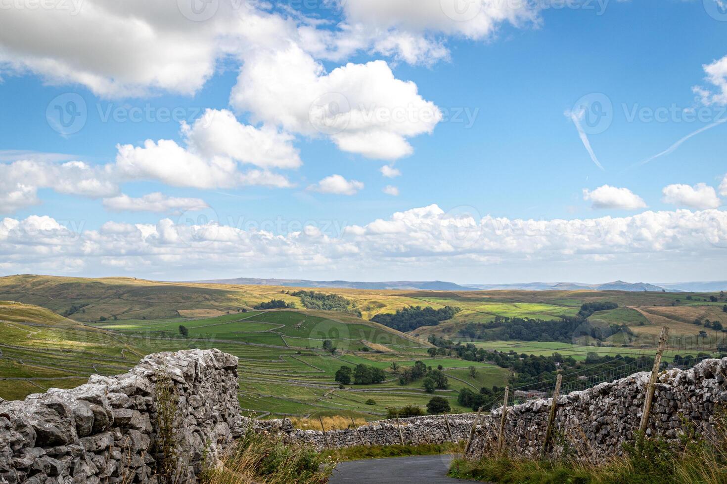 Scenic view of rolling hills and countryside with stone walls under a blue sky with clouds. photo
