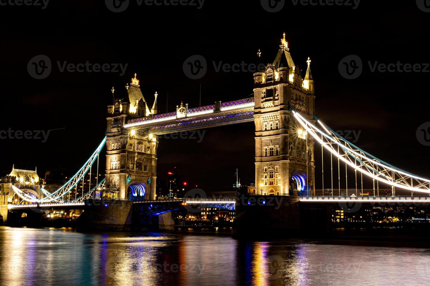 Night view of Tower Bridge in London with illuminated lights reflecting on the Thames River. photo