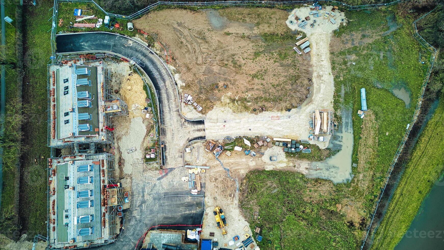 Aerial view of a construction site with excavated land, machinery, and materials, surrounded by greenery. photo