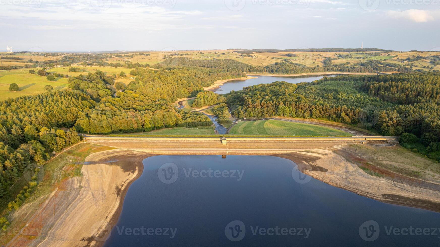 Aerial view of a serene lake with surrounding greenery and a clear sky. photo