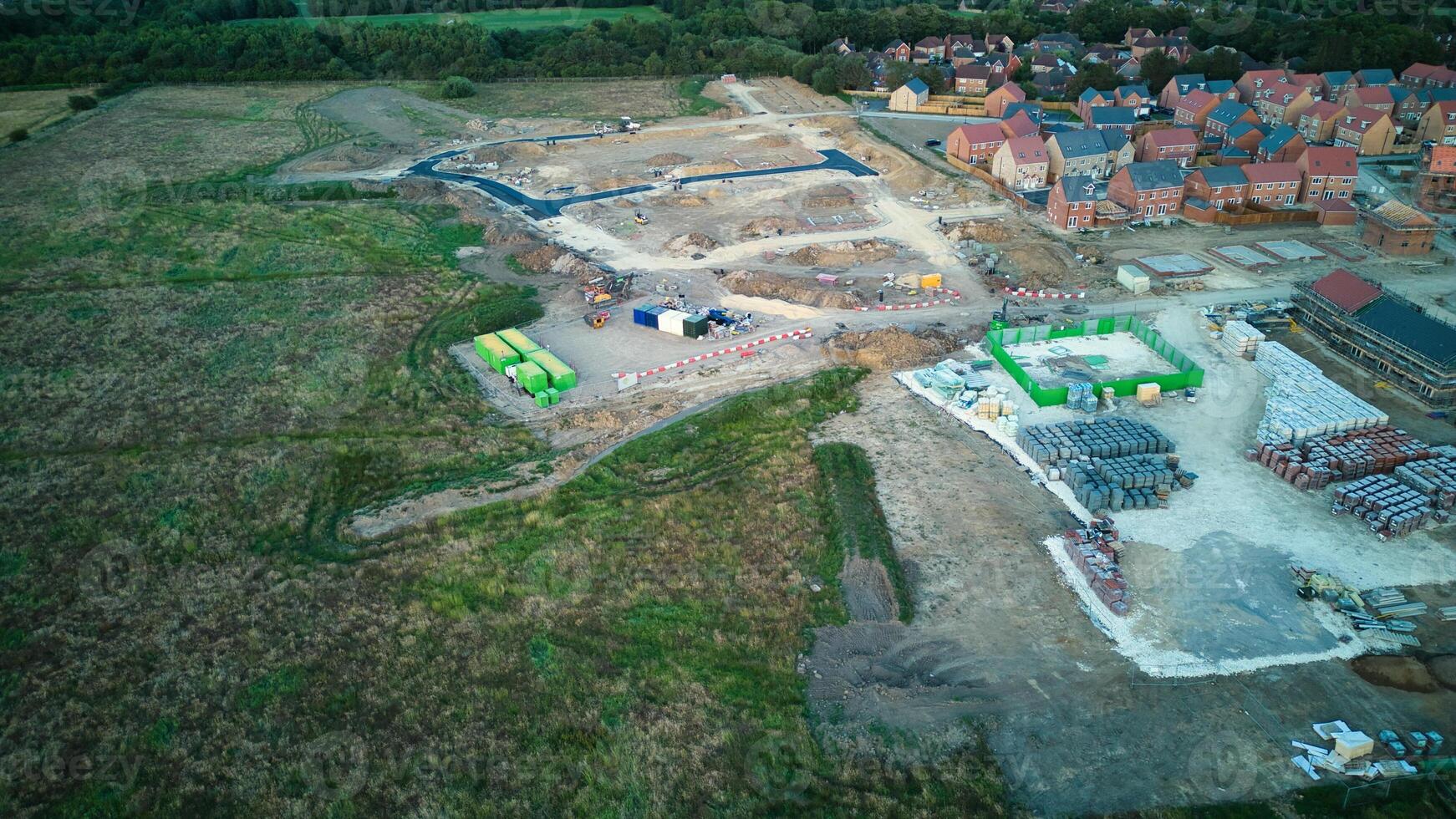 Aerial view of a construction site with materials and machinery near a residential area at dusk. photo
