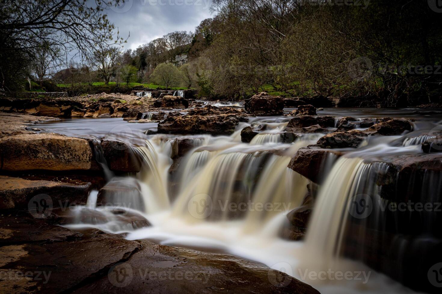 Serene waterfall cascading over rocks with lush greenery in the background, showcasing nature's tranquility in Yorkshire Dales. photo