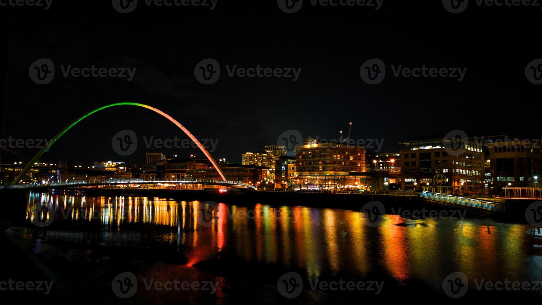 Night cityscape with a colorful arch bridge reflected in the water in Newcastle upon Tyne photo