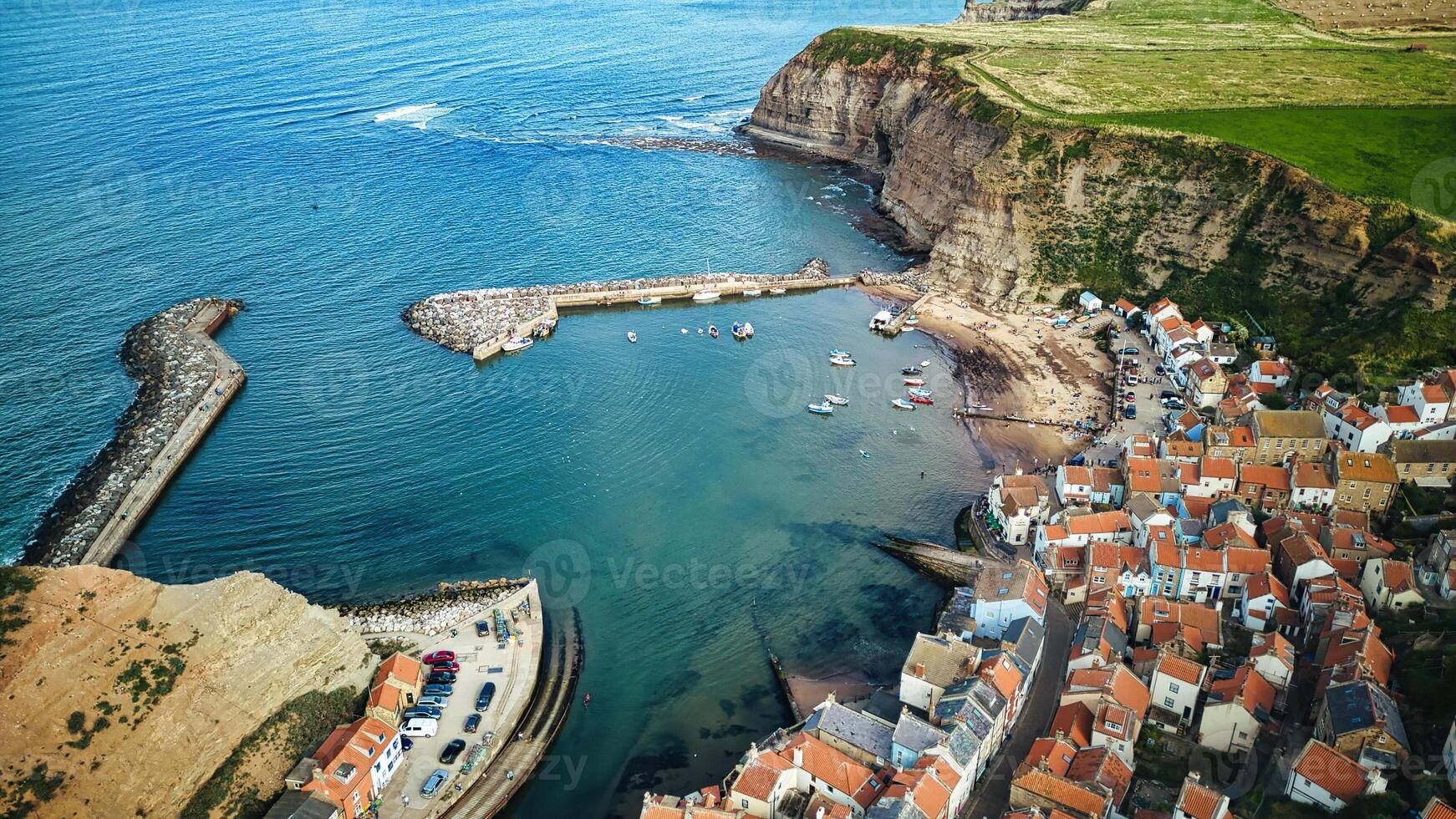 Aerial view of a quaint coastal village with a harbor, surrounded by cliffs and the sea in Staithes, England. photo