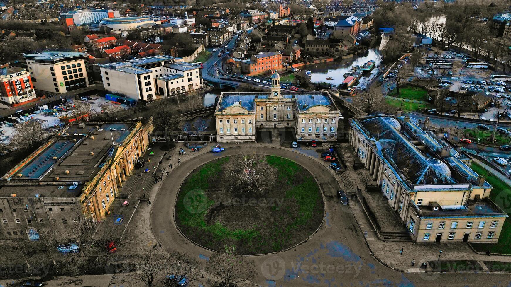 aéreo ver de un histórico circular Roca fortaleza a oscuridad, con rodeando urbano paisaje y puesta de sol cielo en york, norte Yorkshire foto