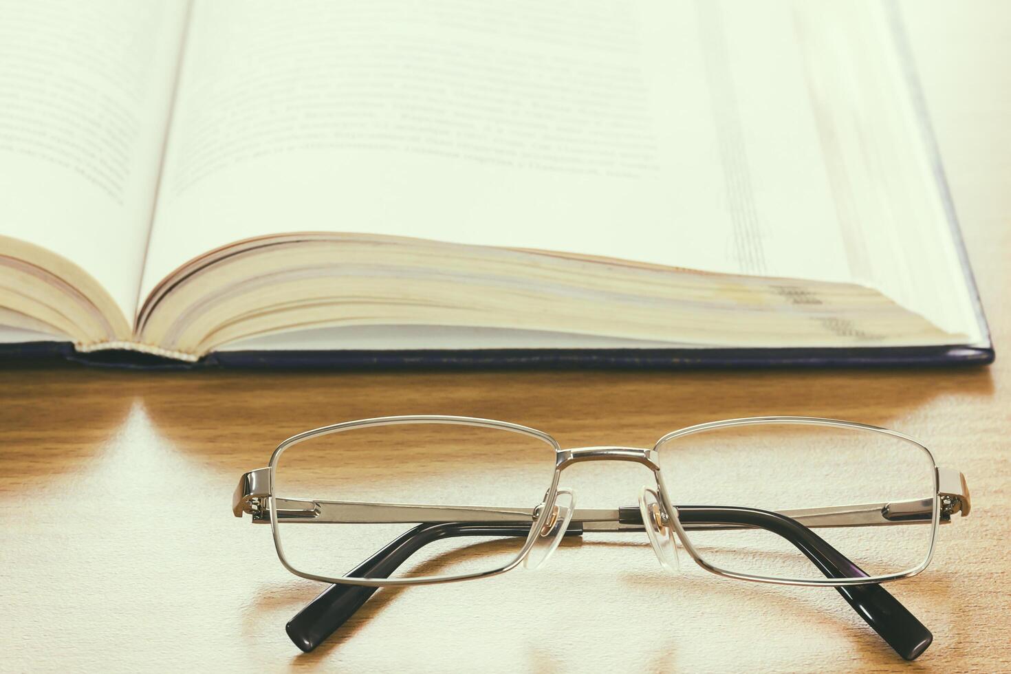 Close up glasses and a book on the desk , vintage style photo