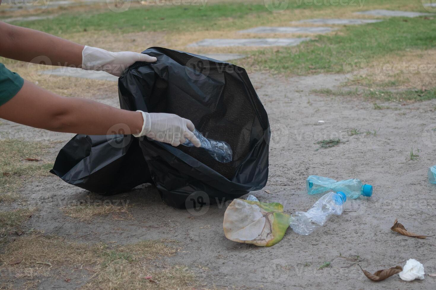 Cleanup volunteers woman picking leaves and plastic bottles into trash garbage bags,the concept of a clean natural environment photo