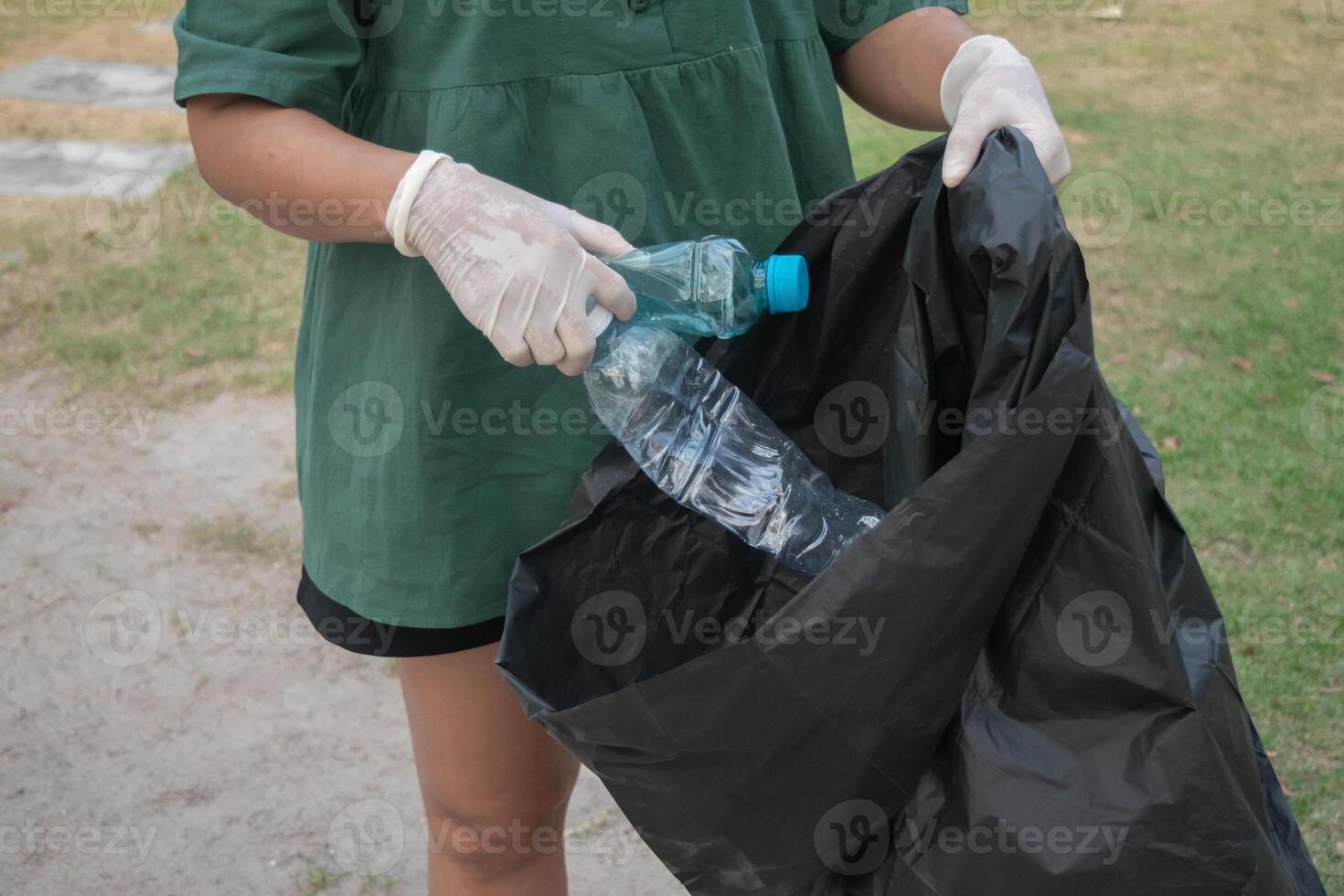 Cleanup volunteers woman picking leaves and plastic bottles into trash garbage bags,the concept of a clean natural environment photo