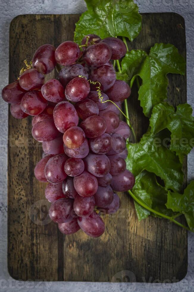 a bunch of grapes on a wooden cutting board photo