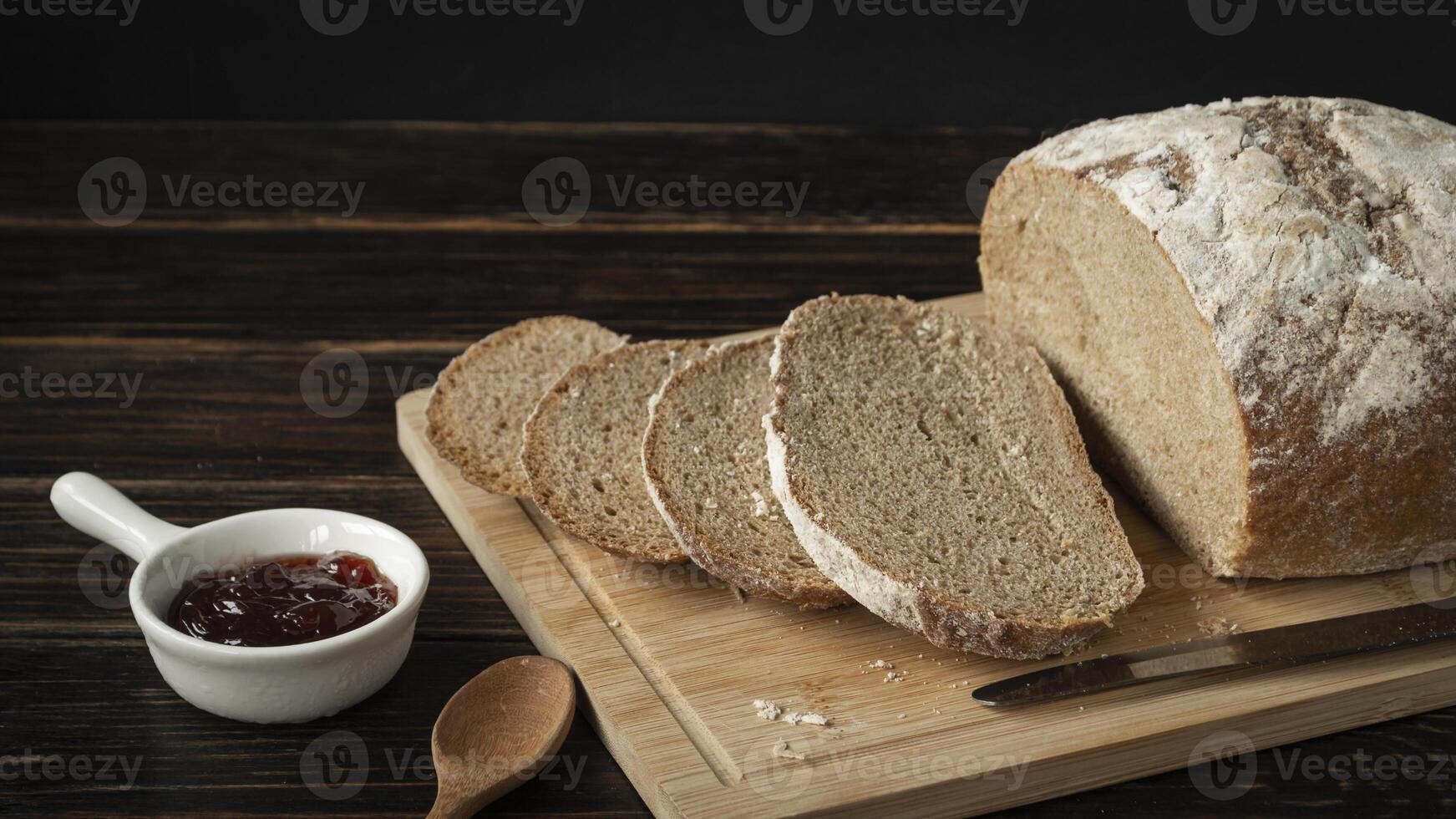bread on a cutting board with jam and a spoon photo