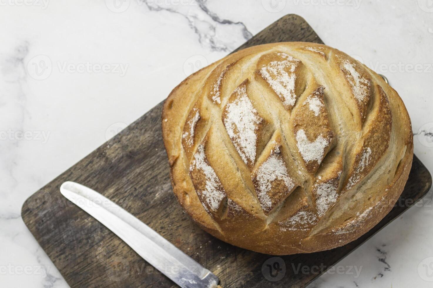 a loaf of bread on a cutting board with a knife photo