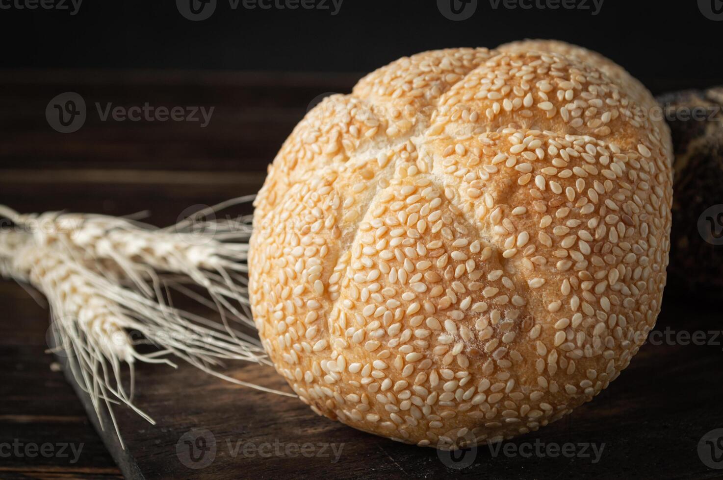 a loaf of bread and some wheat on a wooden table photo