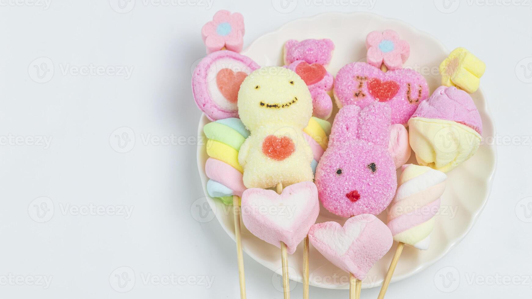 marshmallows and candy on sticks in a plate photo