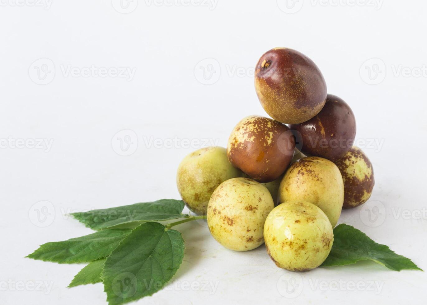 a pile of ripe plums with leaves on a white background photo