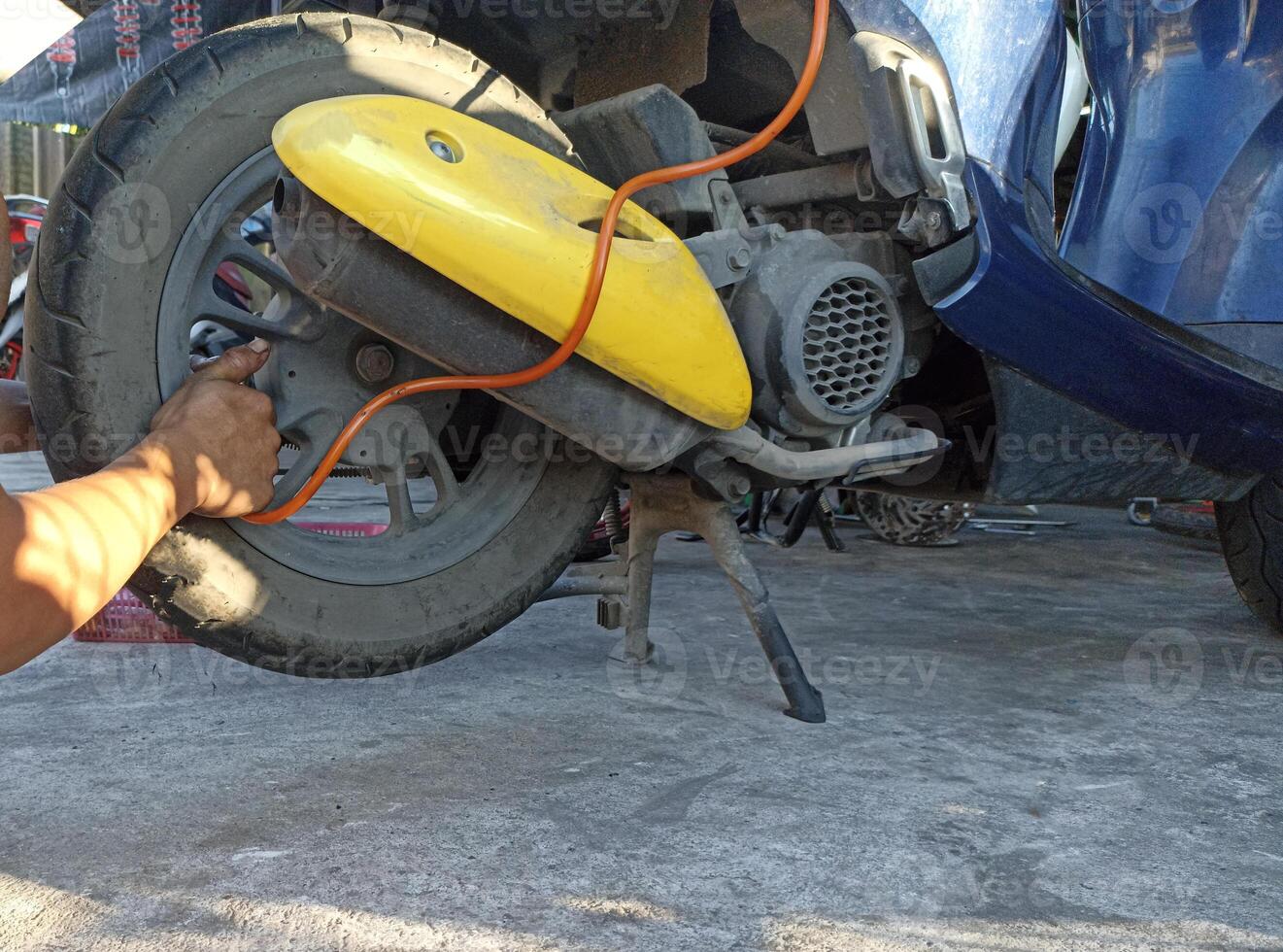 A motorcycle mechanic is adding air to a tire. photo